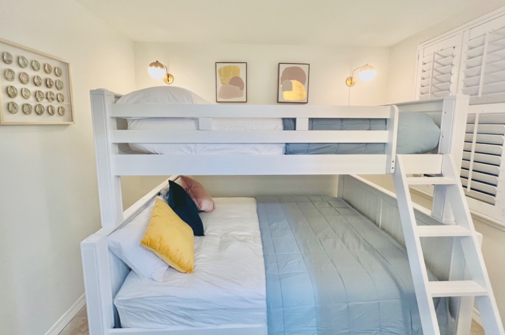 Bunk room with double-over-queen bunk bed, plantation shutters, and built-in ladder
